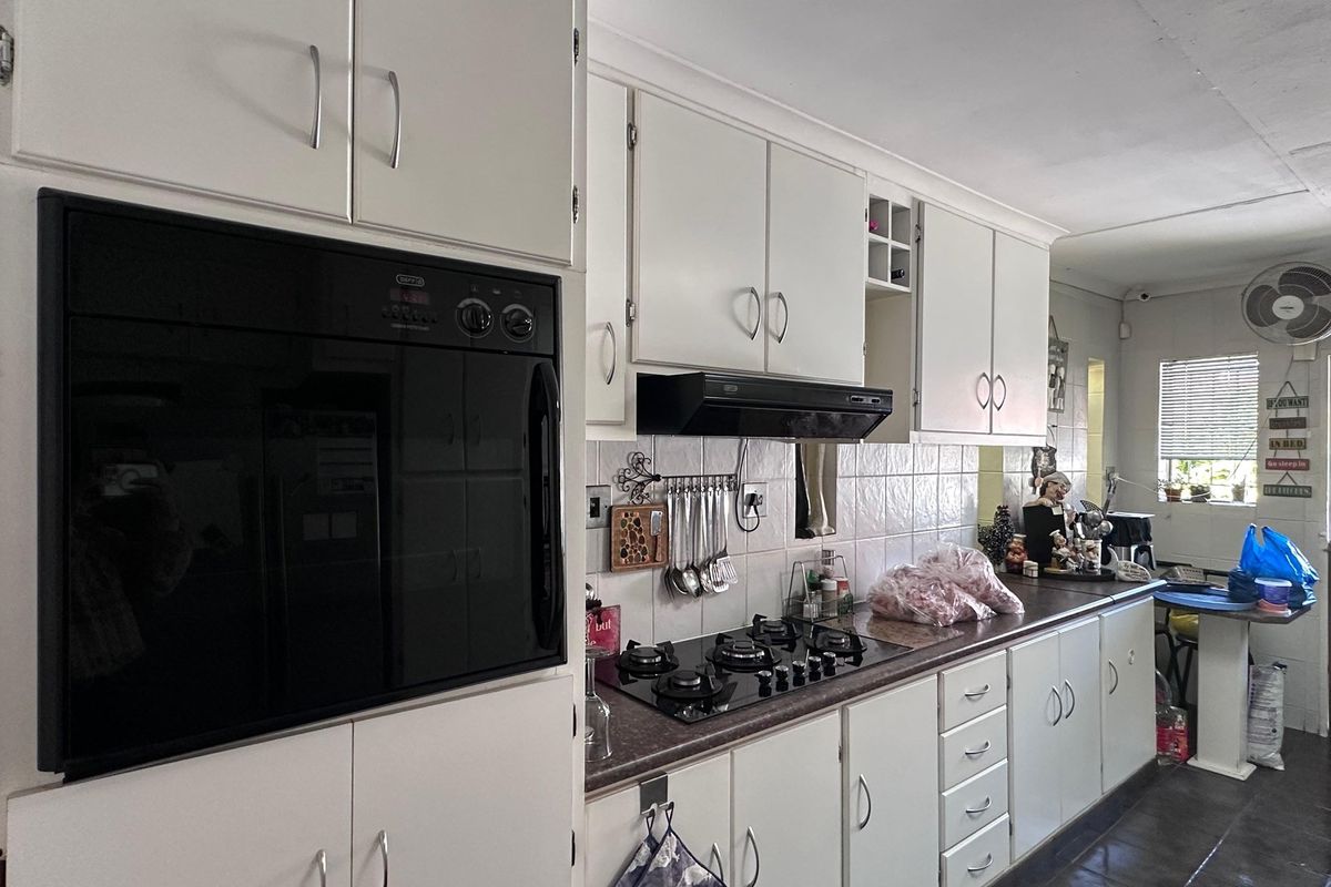 A functional kitchen featuring white cabinetry, a built-in oven, gas hob, extractor fan, and tiled backsplash with laminate countertops.