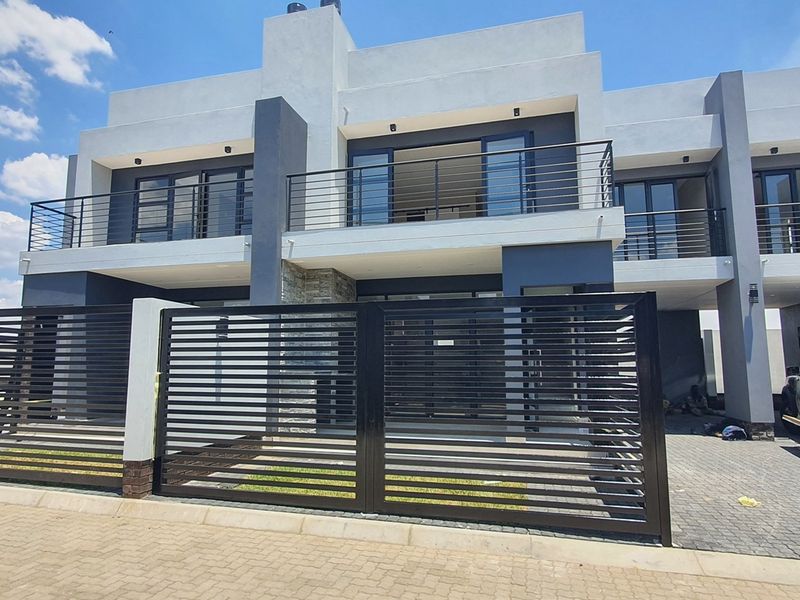 Modern two-story apartment building featuring a contemporary facade, private balconies with metal railings, and a secure gated entrance with paved driveway.