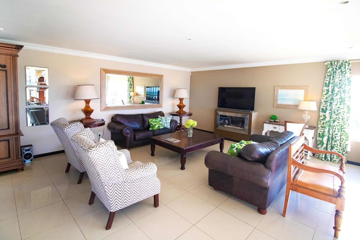 Spacious living room featuring large format floor tiles, recessed downlighting, and a built-in modern fireplace.