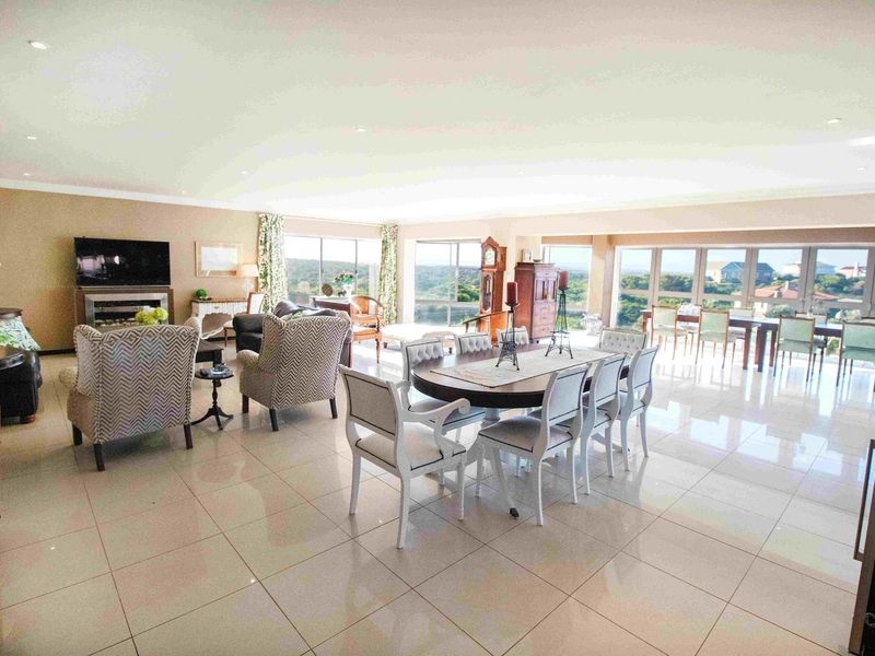 Spacious open-plan living and dining area featuring large windows with scenic views, recessed ceiling lighting, and polished tile flooring throughout.