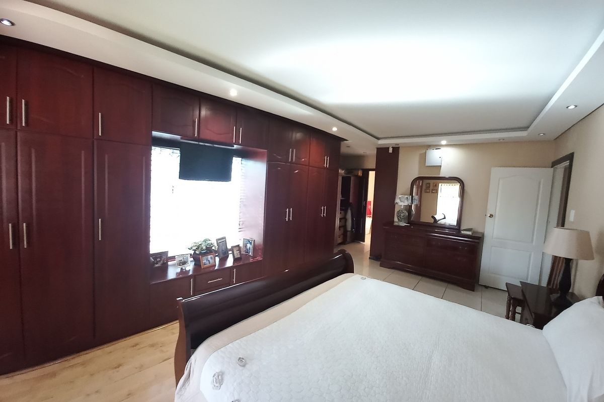 Spacious bedroom featuring extensive built-in dark wood cabinetry, recessed ceiling lighting, and tiled flooring.