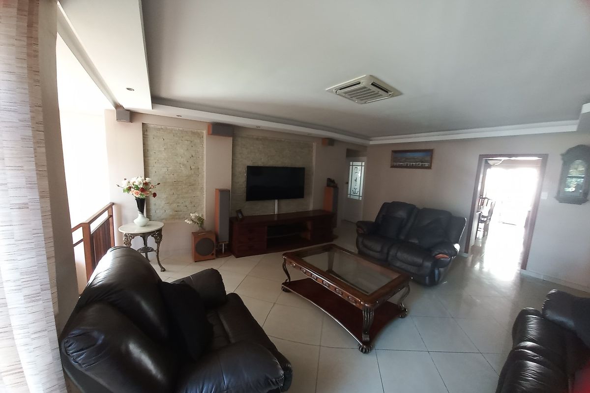 Spacious living room featuring tiled flooring, recessed ceiling lighting, and a built-in stone feature wall for the television area.