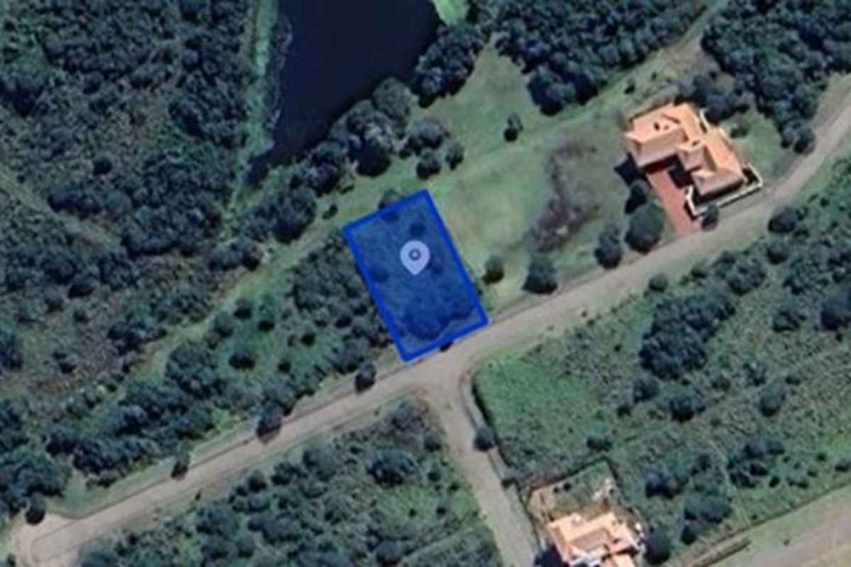 Aerial view of a vacant residential plot situated in a natural, wooded estate setting with nearby water features.