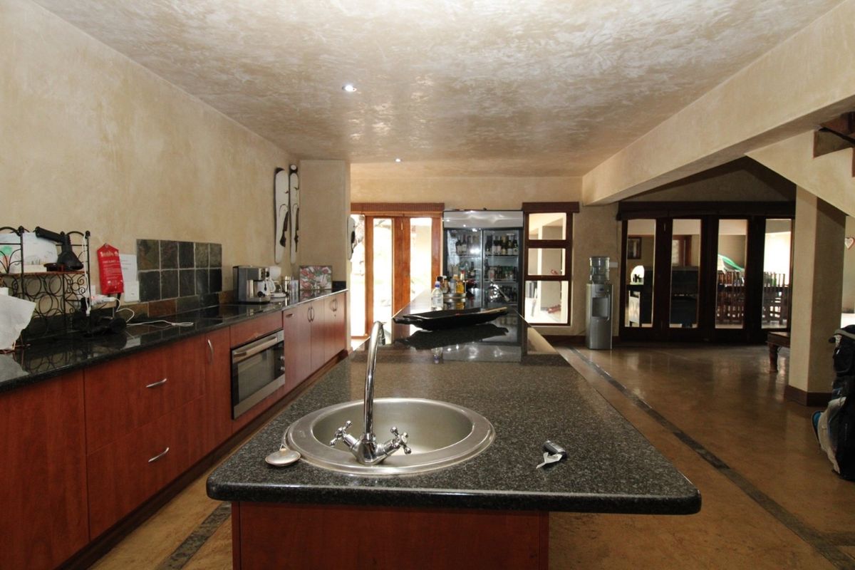 Spacious kitchen featuring a large island with a sink, granite countertops, built-in oven, and warm-toned cabinetry with recessed lighting.