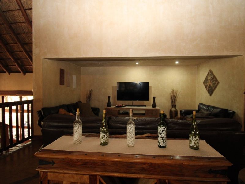 Spacious living room featuring a high vaulted thatched ceiling, recessed lighting, and a warm, textured wall finish.