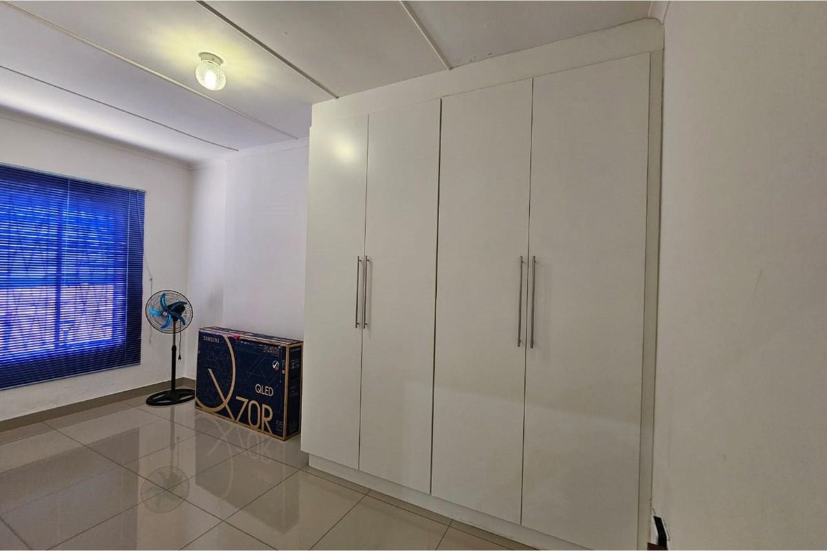 A bedroom featuring built-in wardrobes with white cabinetry and tiled flooring.