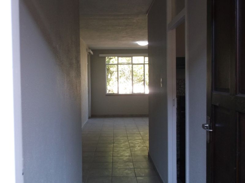 A view from the entrance hallway looking towards an open living area with tiled flooring and natural light.