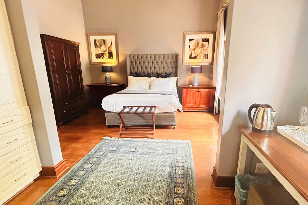 A well-maintained bedroom featuring warm timber flooring, high ceilings, and neutral wall tones, providing a comfortable and inviting living space.