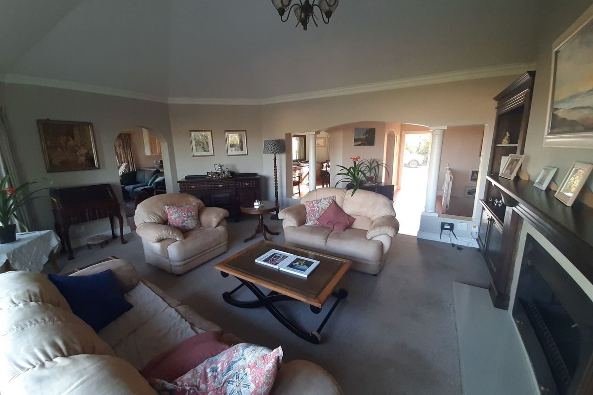 Spacious living room featuring a fireplace, built-in shelving, and architectural archways with decorative columns, creating a warm and inviting atmosphere.