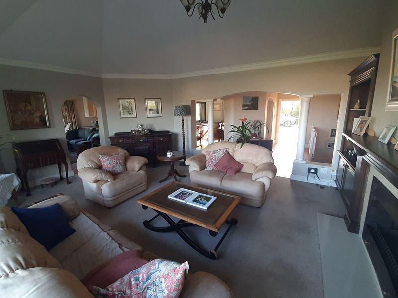 Spacious living room featuring a fireplace, built-in shelving, and architectural archways with decorative columns, creating a warm and inviting atmosphere.
