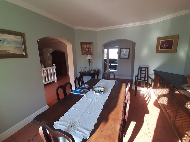 A dining room featuring terracotta floor tiles, crown molding, and arched doorways leading to adjacent living spaces.