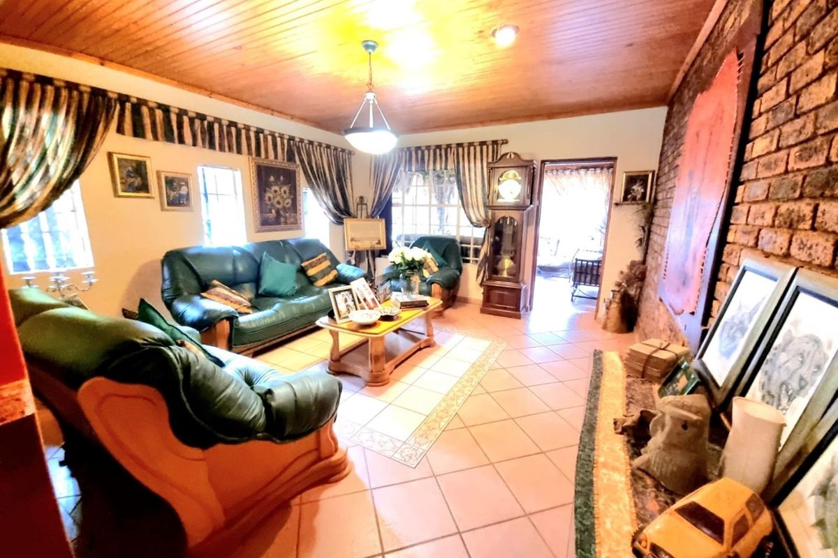 A rustic living room featuring a brick feature wall, tiled flooring, and a timber-paneled ceiling, providing a warm and traditional atmosphere.