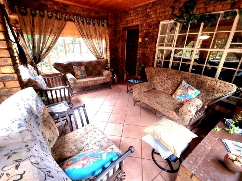 A rustic enclosed patio featuring exposed face-brick walls, timber-clad ceiling, and large grid-pane windows, providing a warm and inviting space for relaxation.