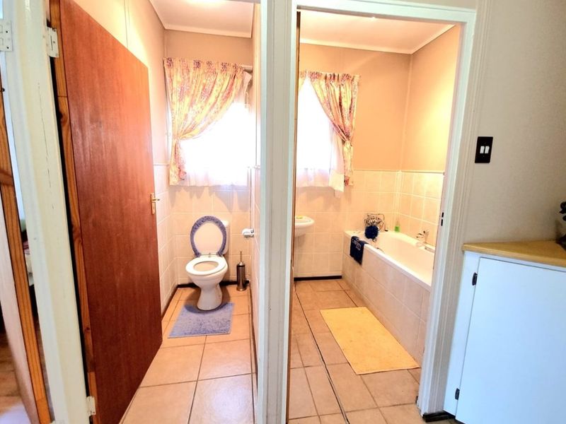 A functional bathroom featuring a separate toilet area and a bathtub with tiled surrounds, offering a practical layout for a farm property.