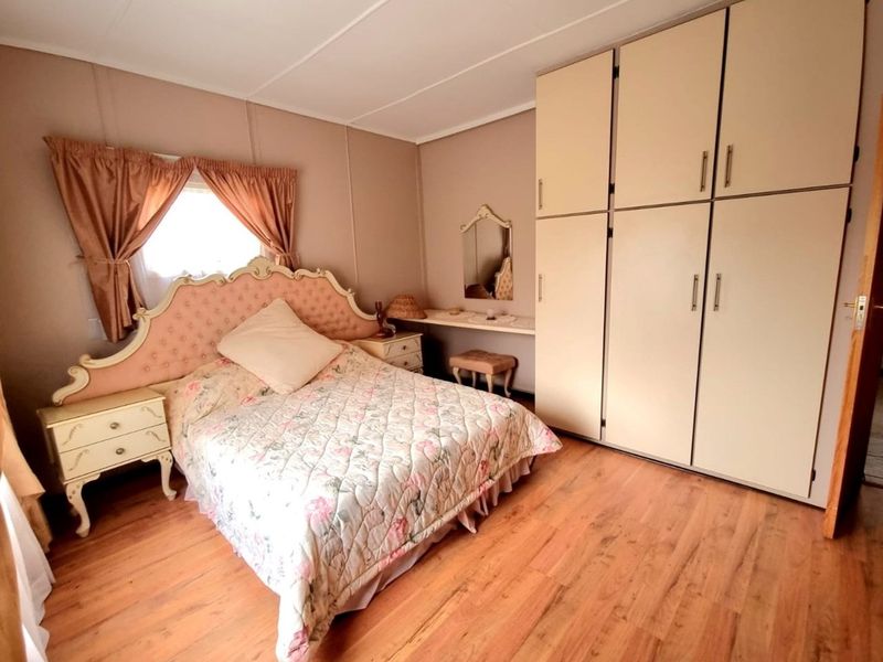 A bedroom featuring built-in cabinetry, wood-look flooring, and a window with curtains, offering a functional and lived-in space.