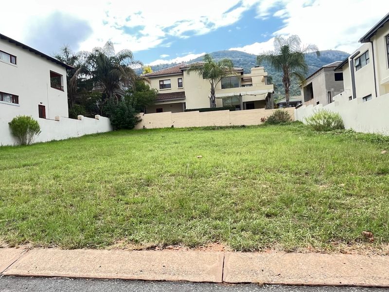 A vacant residential plot of land featuring a grassed surface, enclosed by perimeter boundary walls, situated within a developed residential estate.