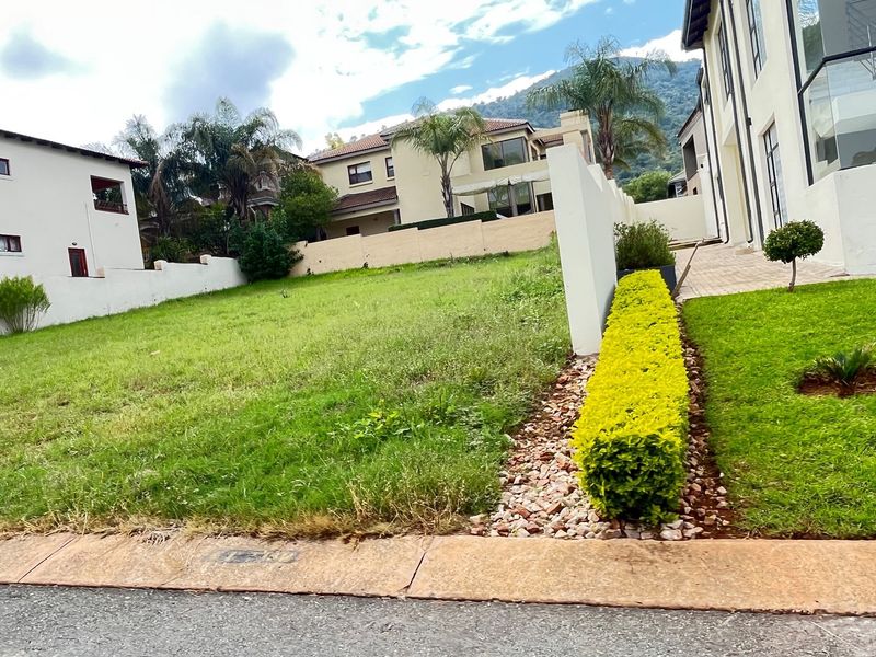 A vacant residential plot featuring established lawn, perimeter boundary walls, and manicured garden hedging, situated within a developed residential estate.