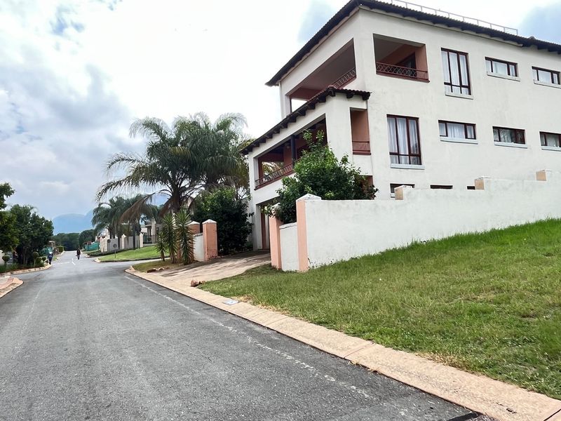 Street view of a multi-story residential property featuring a paved driveway, perimeter boundary wall, and covered balconies.
