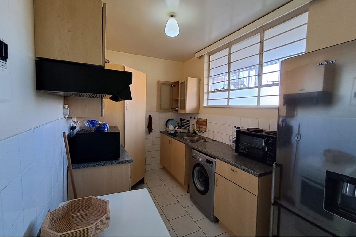 Functional kitchen featuring light wood cabinetry, granite-look countertops, tiled splashbacks, and integrated laundry plumbing.