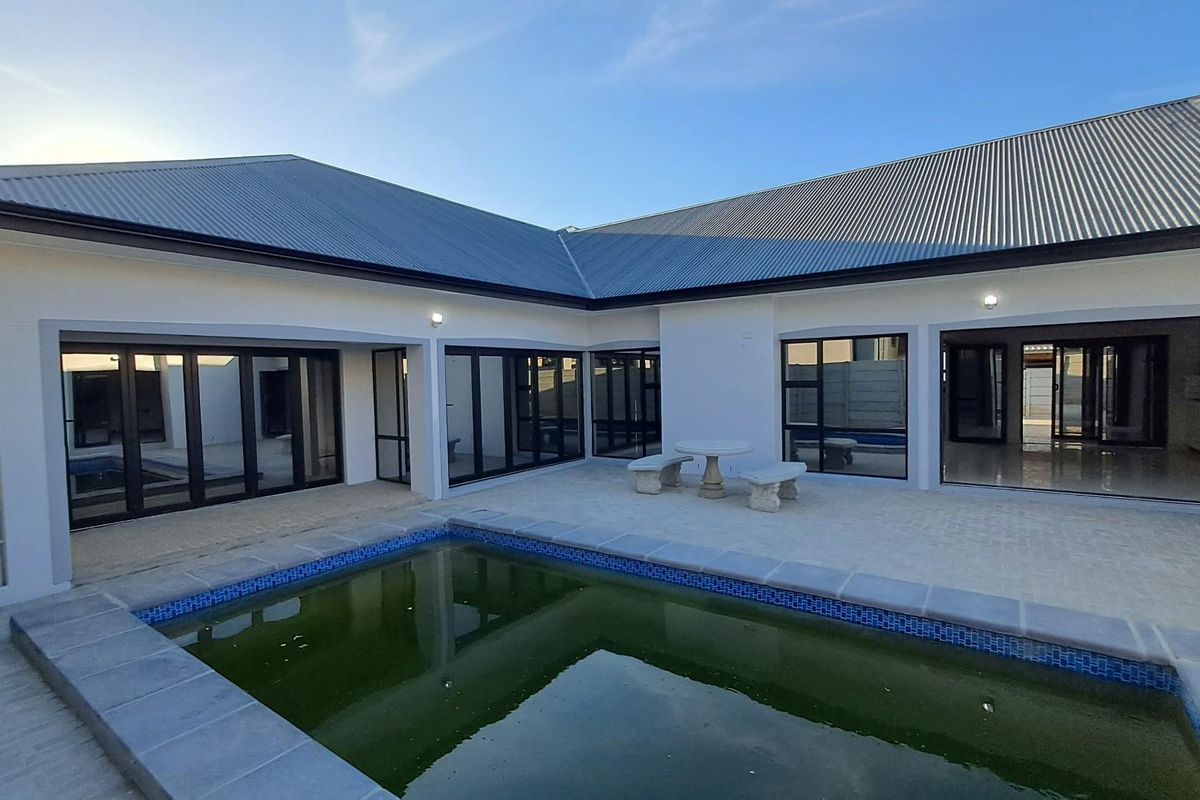 Rear exterior view featuring a swimming pool, paved patio area, and large glass sliding doors providing seamless indoor-outdoor flow.