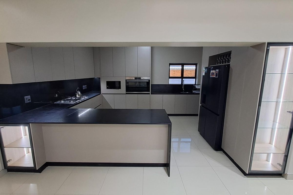Modern kitchen featuring sleek cabinetry, dark stone countertops, integrated oven, built-in microwave, gas hob, and polished floor tiles.