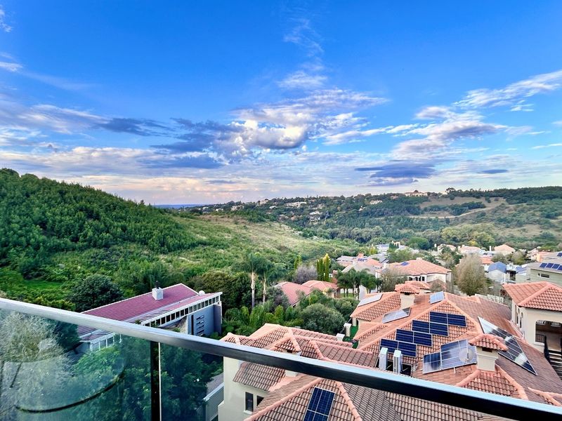 Elevated scenic view overlooking the surrounding residential estate and lush green hills, featuring a modern glass balustrade in the foreground.