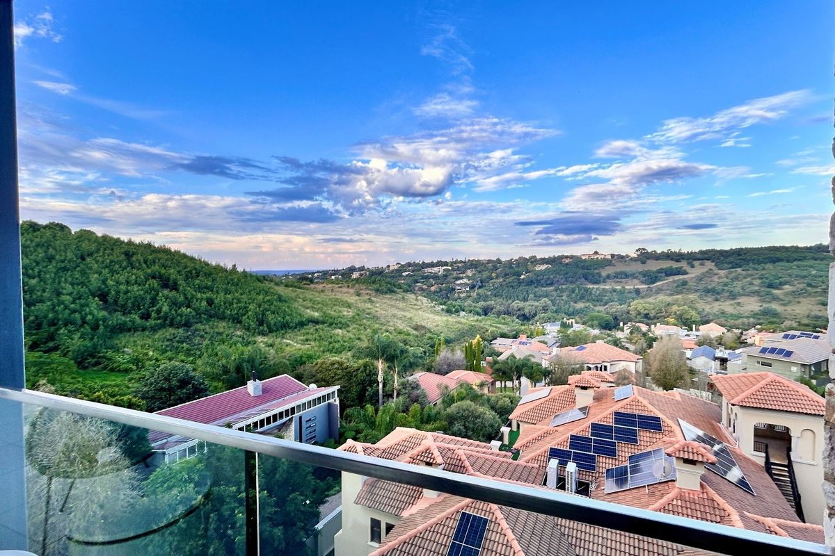 Elevated scenic view overlooking the surrounding residential estate and lush green hills, featuring a modern glass balustrade in the foreground.