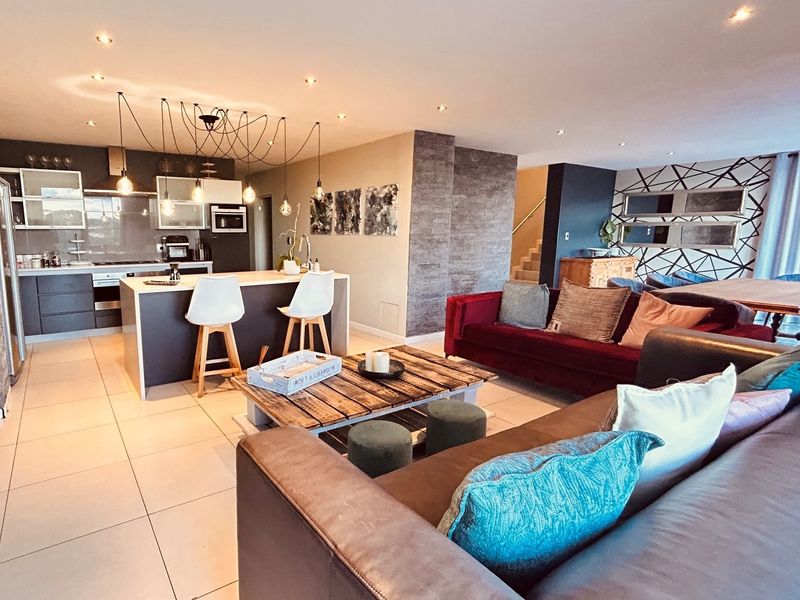 Spacious open-plan living area featuring a modern kitchen with a central island, sleek cabinetry, and contemporary tiled flooring throughout the integrated space.
