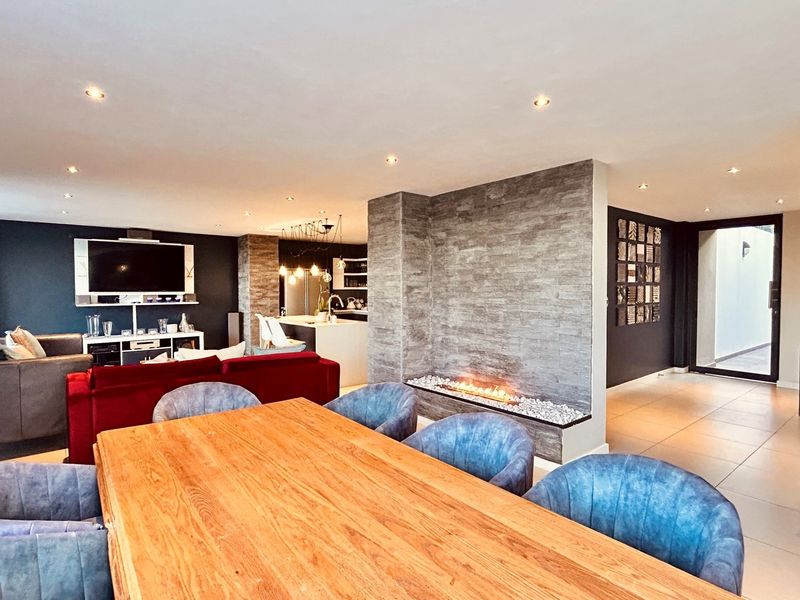 Spacious open-plan living and dining area featuring a modern stone-clad fireplace, recessed lighting, and seamless flow into the contemporary kitchen.