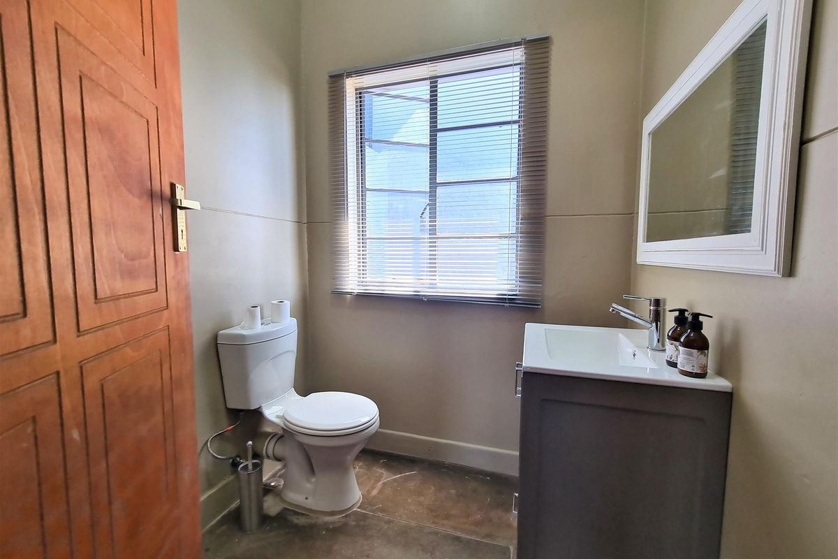A functional bathroom featuring a modern vanity, a standard toilet, and a window with fitted blinds.