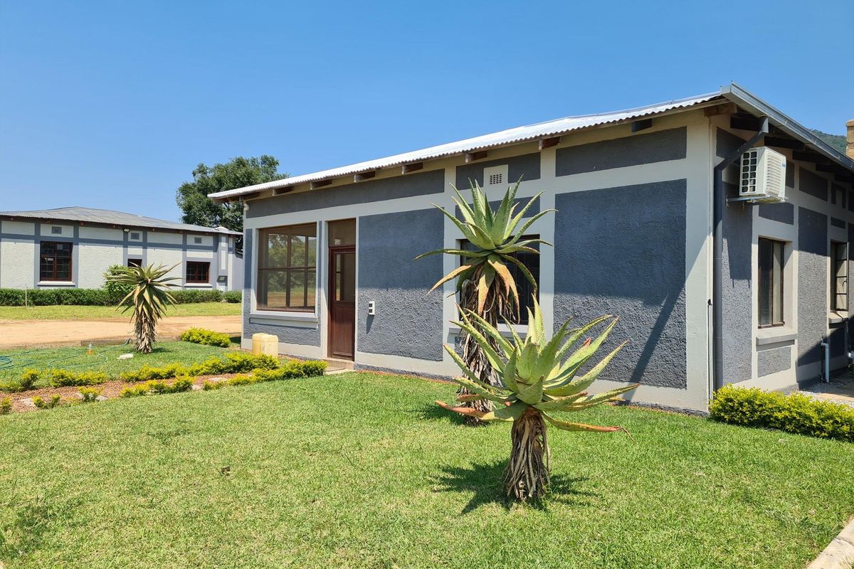 Exterior view of a well-maintained farm building featuring a grey textured facade, corrugated metal roof, and an integrated air conditioning unit.