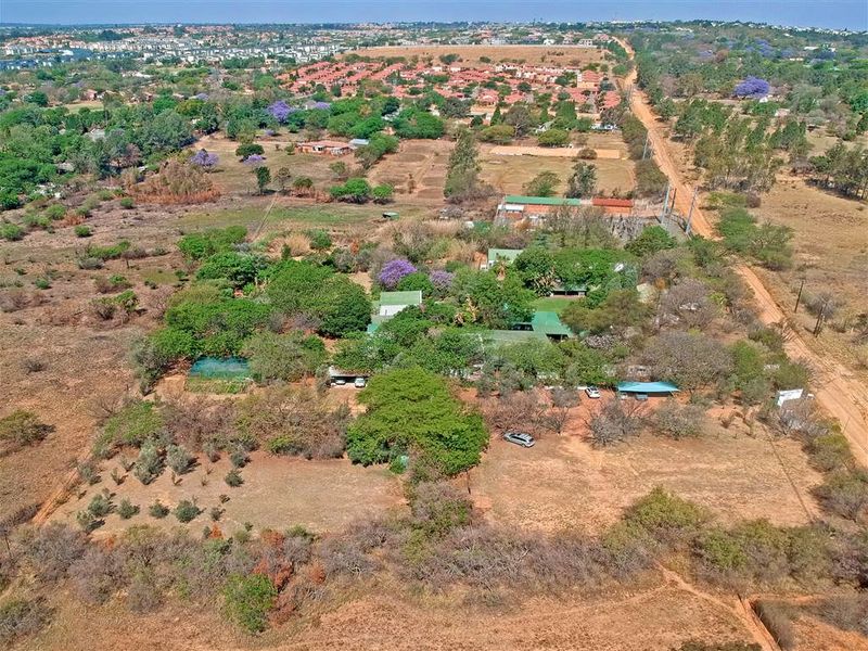 An aerial view of a large, expansive property featuring mature trees, established grounds, and multiple outbuildings set within a semi-rural landscape.