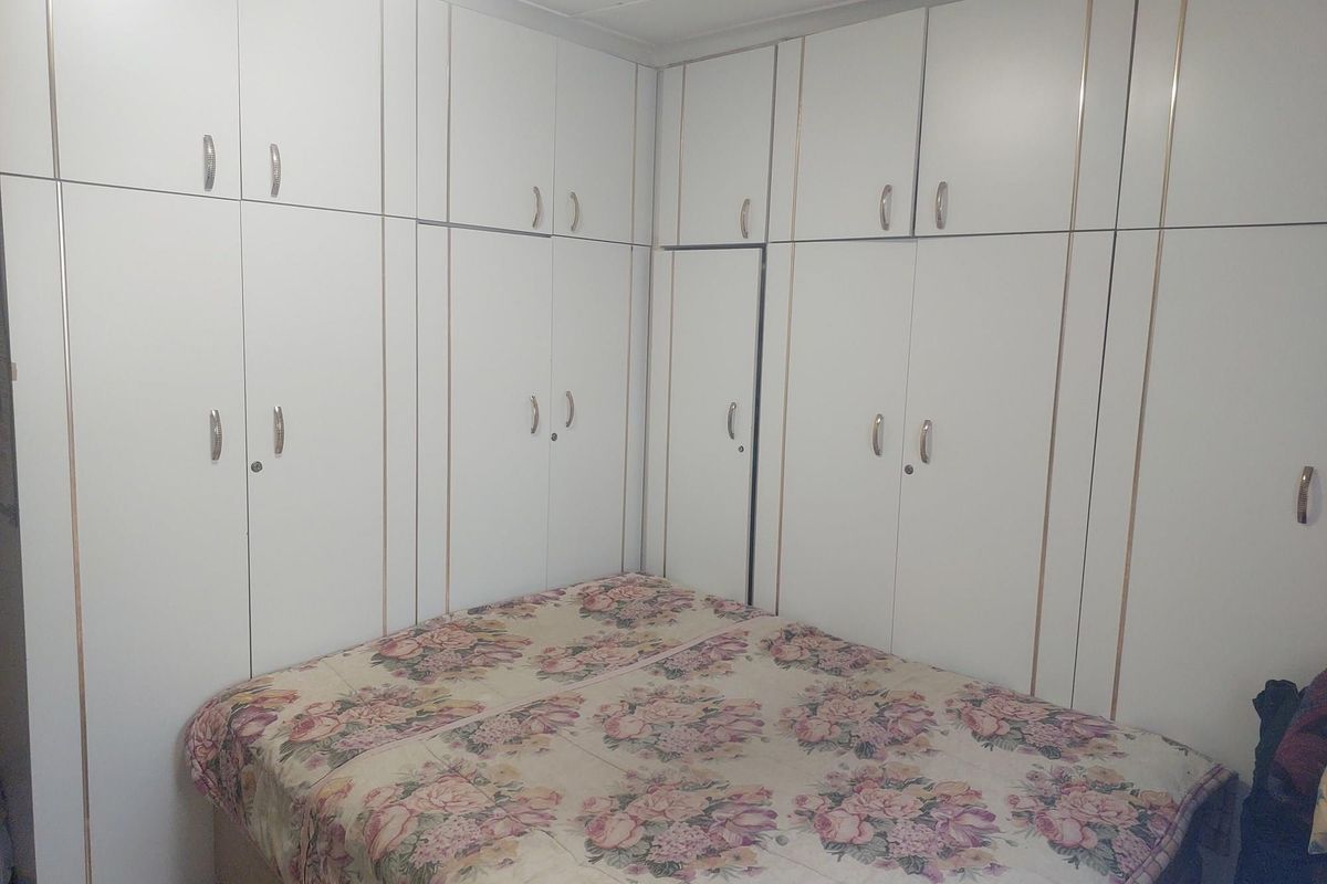 A bedroom featuring extensive floor-to-ceiling built-in cabinetry with white doors and metallic handles, providing ample integrated storage space.