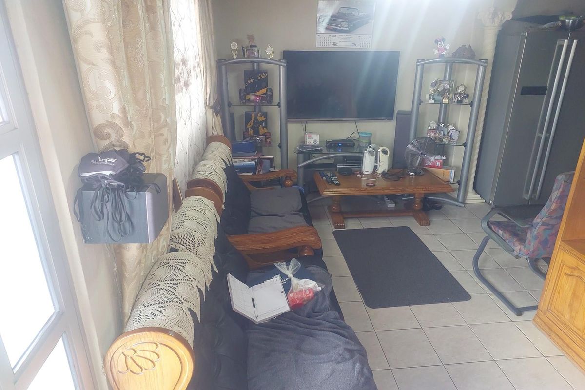 A living room area featuring tiled flooring and a wall-mounted television setup.