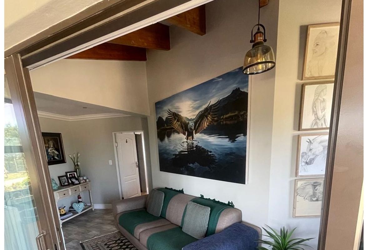 A living area featuring exposed timber ceiling beams, tiled flooring, and a sliding door leading to an outdoor space.