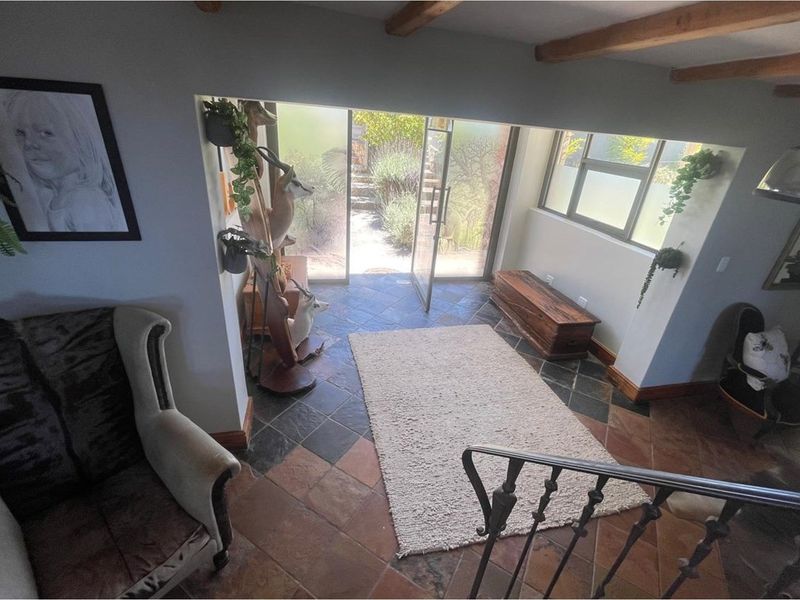 Entrance foyer featuring slate tile flooring, exposed timber ceiling beams, and direct access to the rear garden through glass sliding doors.