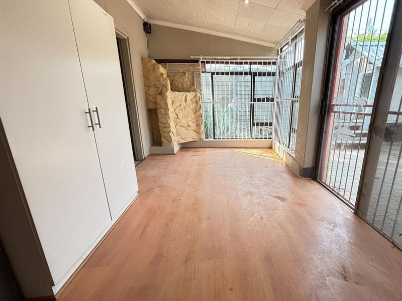 Enclosed patio area featuring laminate flooring, built-in storage, and security bars, offering a versatile space with potential for modernization.