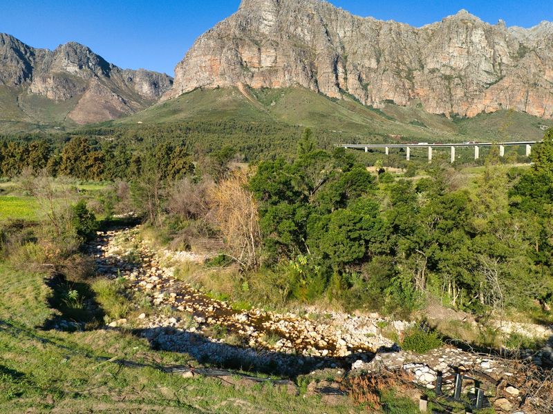 Scenic landscape view featuring a rocky riverbed set against a dramatic mountain range backdrop.