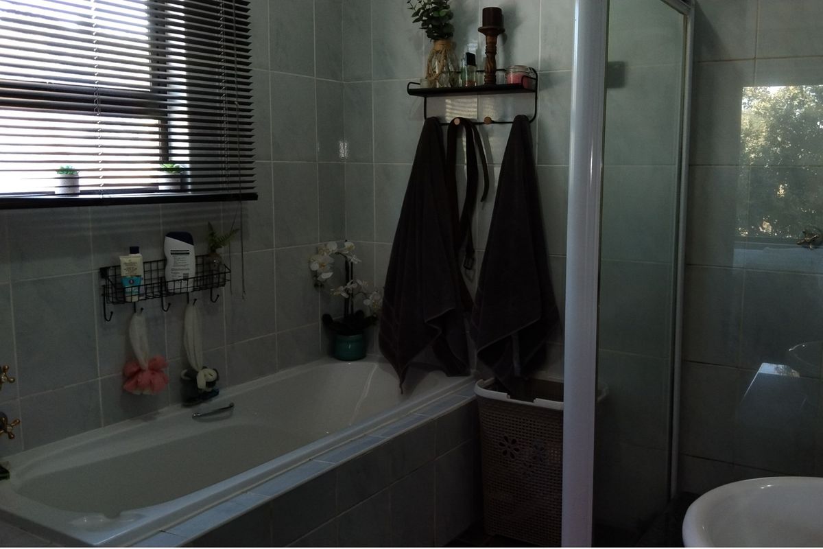 A functional bathroom featuring a built-in bathtub, a separate shower enclosure, and tiled wall finishes.