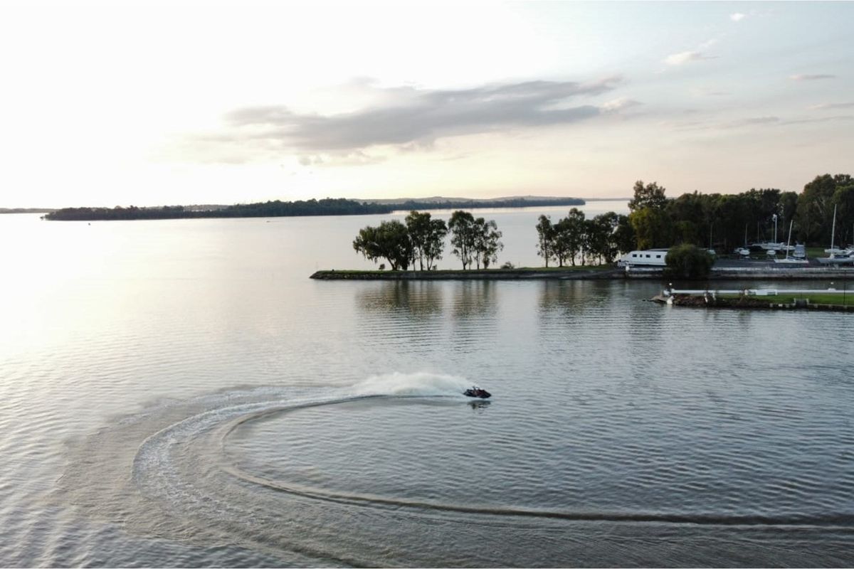 Aerial view of a tranquil lake setting featuring a distant shoreline with trees and a calm water surface.