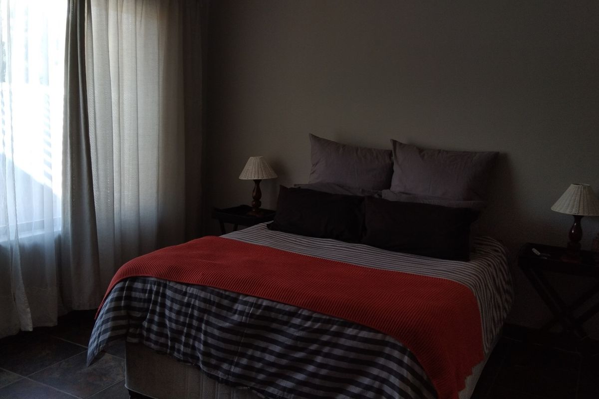 A dimly lit bedroom featuring tiled flooring and large window with curtains.