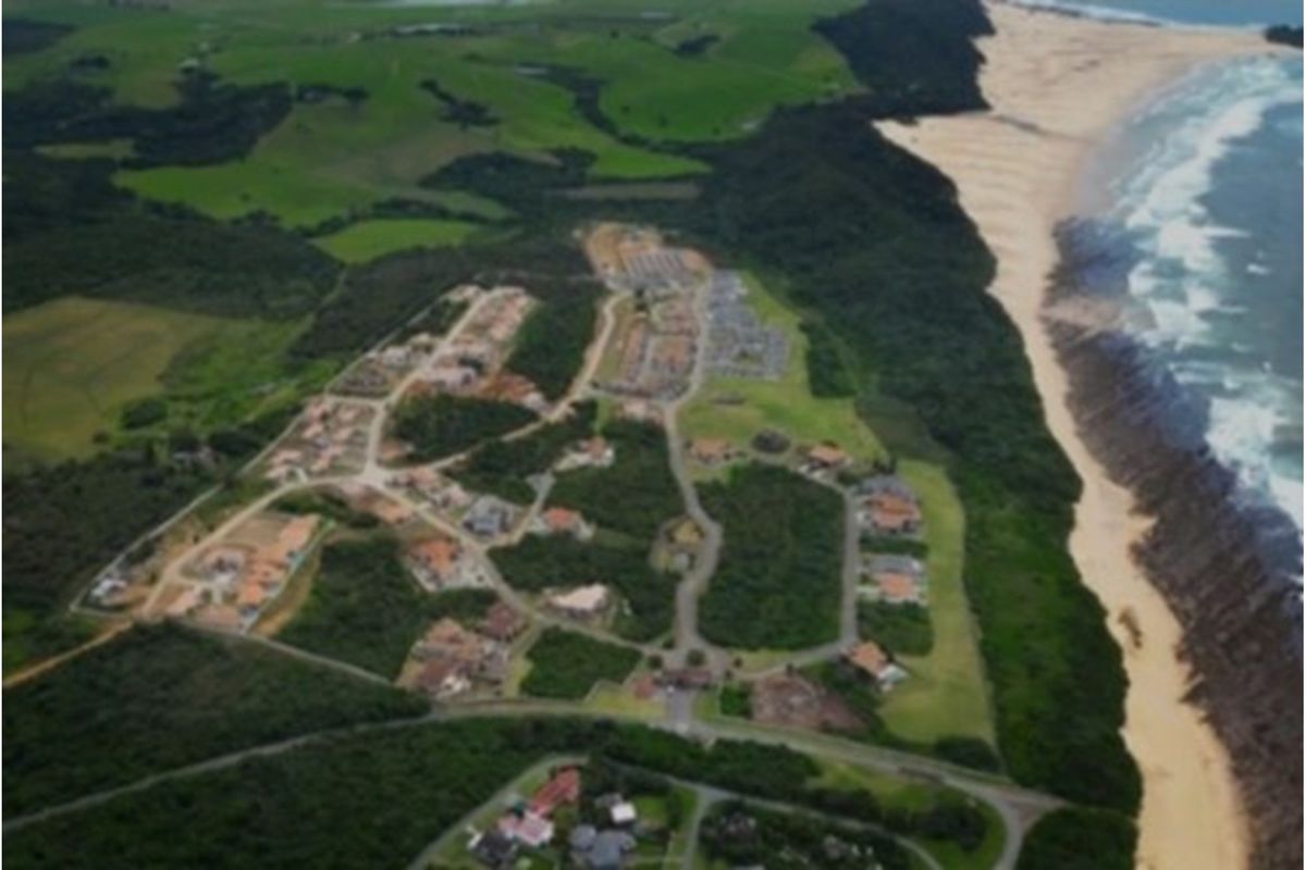 An aerial view of a coastal residential estate featuring established road infrastructure and proximity to the beach and natural landscape.