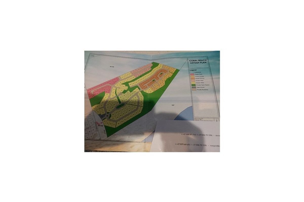A printed layout plan for the Coral Beach residential development, showing various plot types and site zoning.