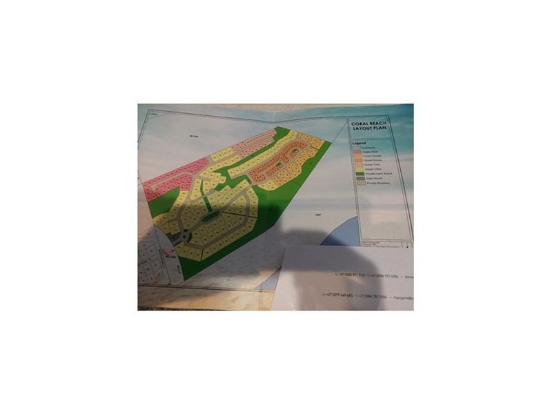 A printed layout plan for the Coral Beach residential development, showing various plot types and site infrastructure.
