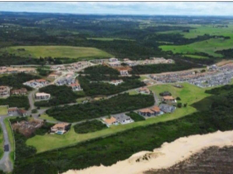 An aerial view of a coastal residential estate featuring established housing, road infrastructure, and surrounding natural landscape.