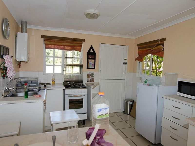 A functional kitchen featuring built-in cabinetry, a gas stove, stainless steel sink, and tiled flooring, offering a practical layout for daily meal preparation.