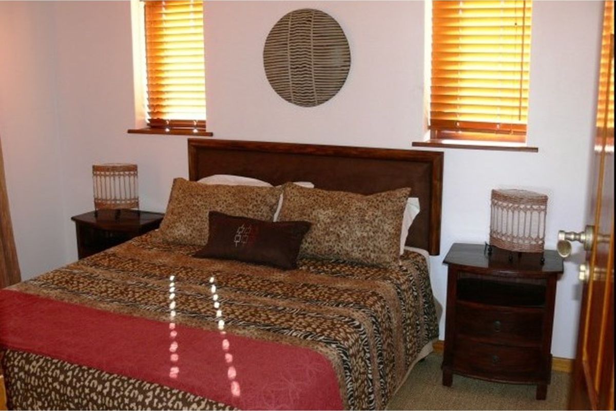 A bedroom featuring dual windows with wooden blinds and neutral wall finishes.