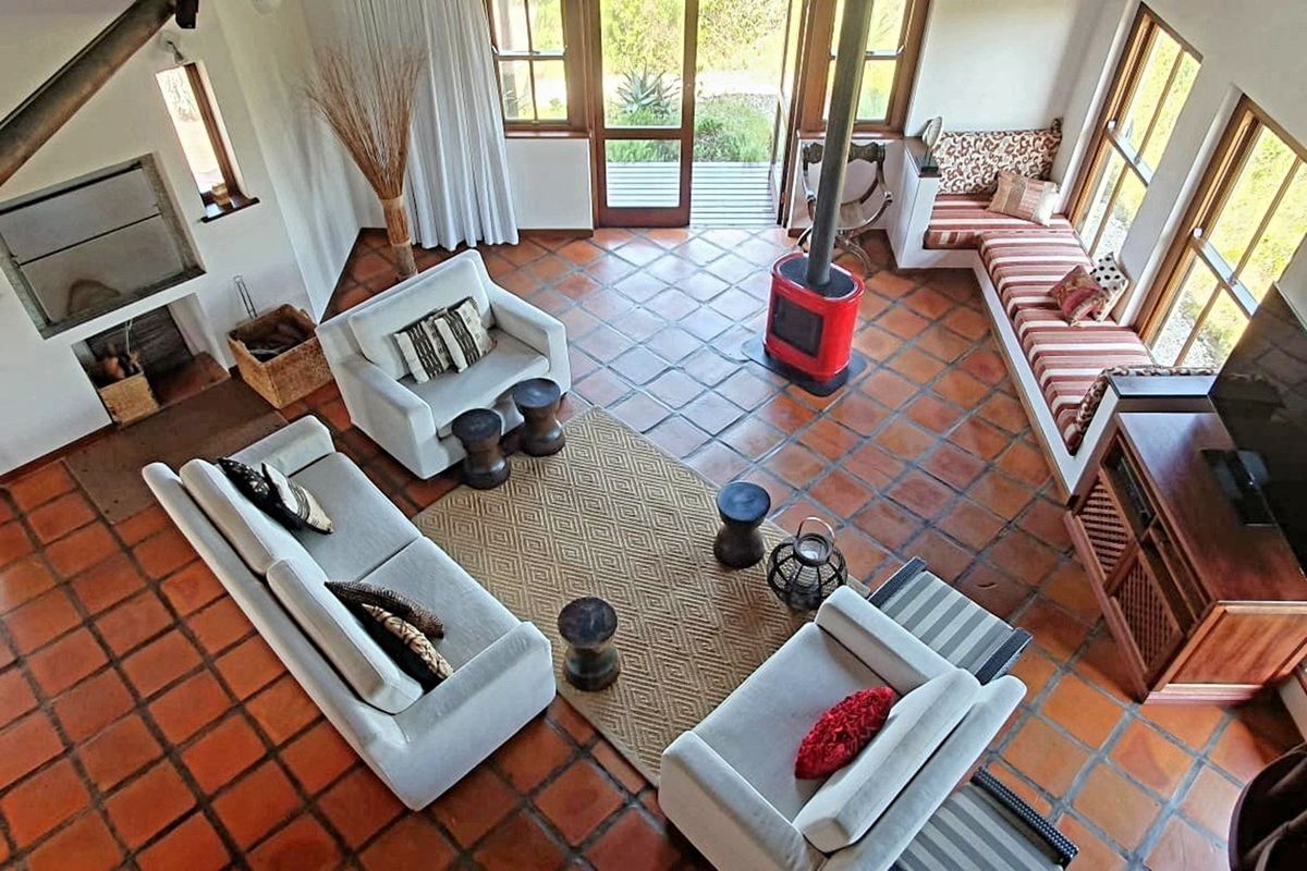 Spacious living room featuring terracotta floor tiles, a built-in fireplace, a freestanding wood-burning stove, and large windows with direct access to the patio.