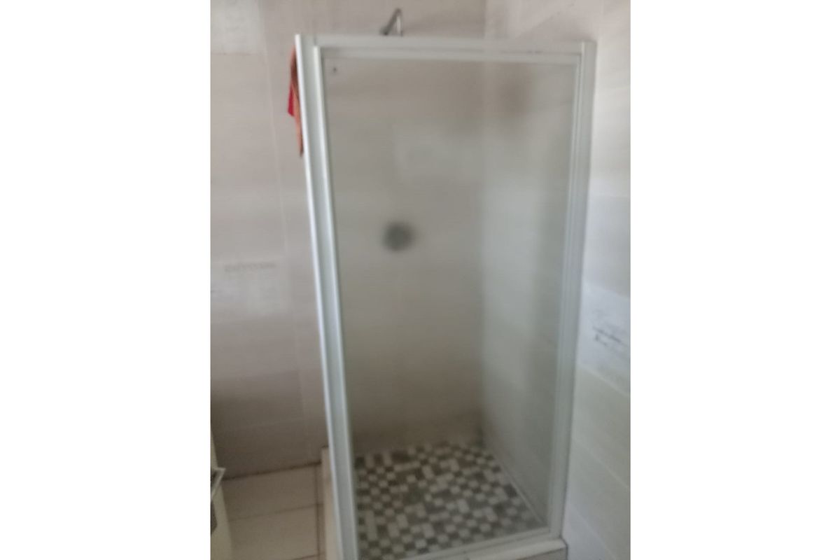 A functional bathroom shower enclosure featuring tiled walls and a mosaic-tiled shower floor.