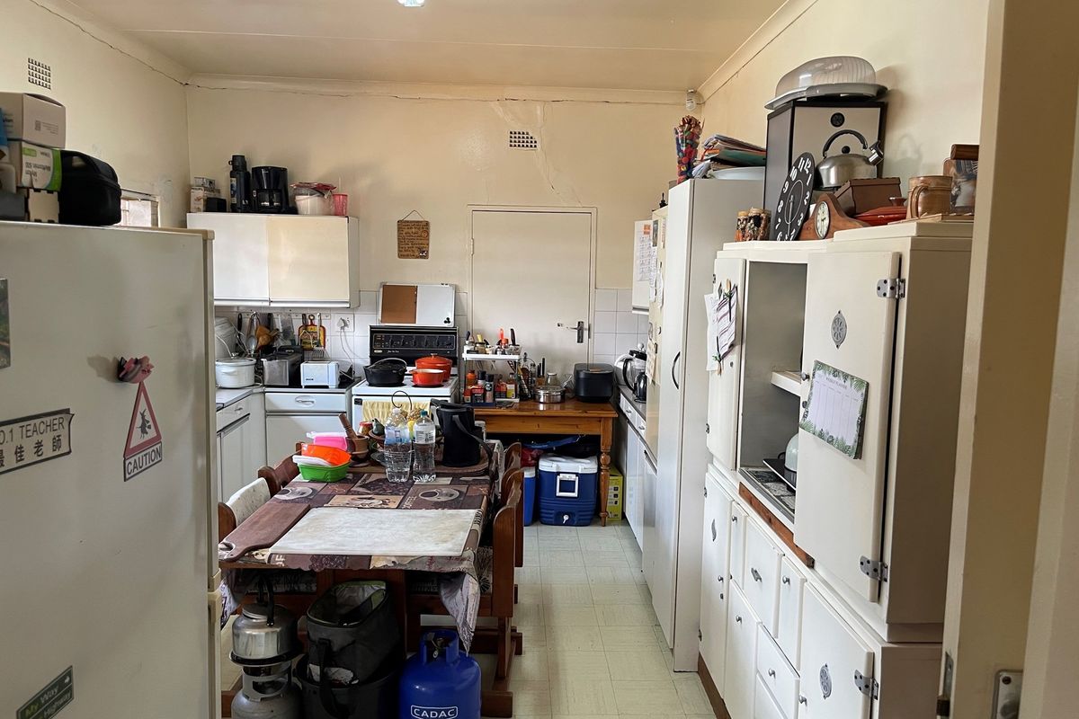 A functional kitchen space featuring built-in cabinetry, a stove, and tiled flooring, offering potential for modernization and layout optimization.